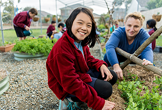 Two children in school uniforms gardening
