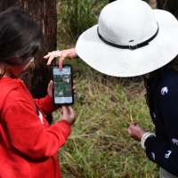 A young girl and a woman use the iNaturalist app to log native plants 