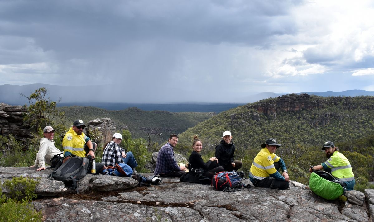 Image of a team of people sitting on a mountain undertaking the Brush-tailed Rock-wallaby monitoring by the Grampians Ark program.