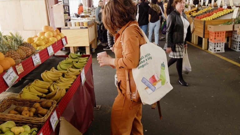 Woman shopping at an outdoor market with various fruits displayed