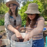 Two people wearing hats planting into a pot