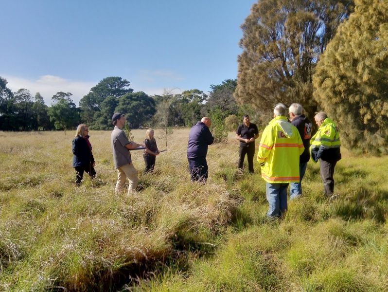 Photo showing people standing around in grassland