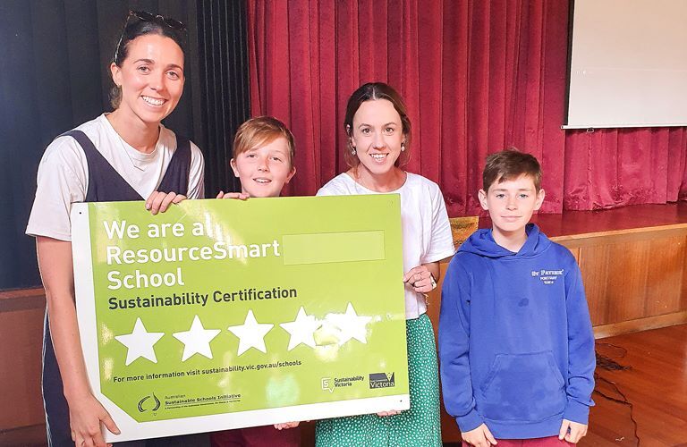 2 women and 2 children holding a large green sign displaying a ResourceSmart School Sustainability Certification with 4 out of 5 stars highlighted