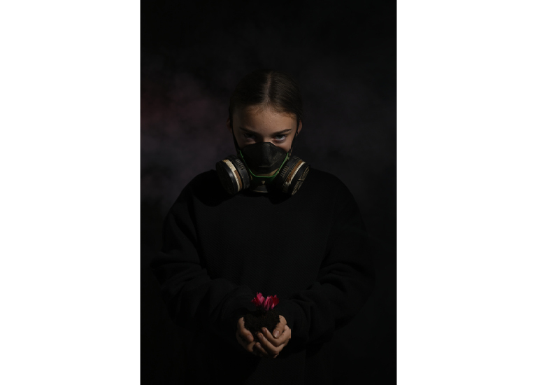 Picture of a girl in a mask holding a flower in darkness