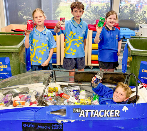 students posing in front of recycling bins
