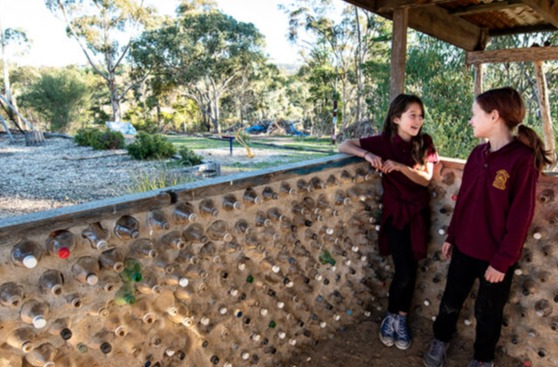 2 kids talking at school overlooking the yard (greenery)
