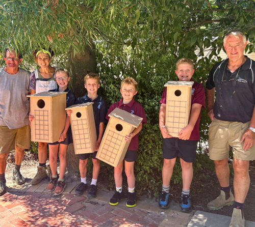 Students and teachers holding habitat box installations